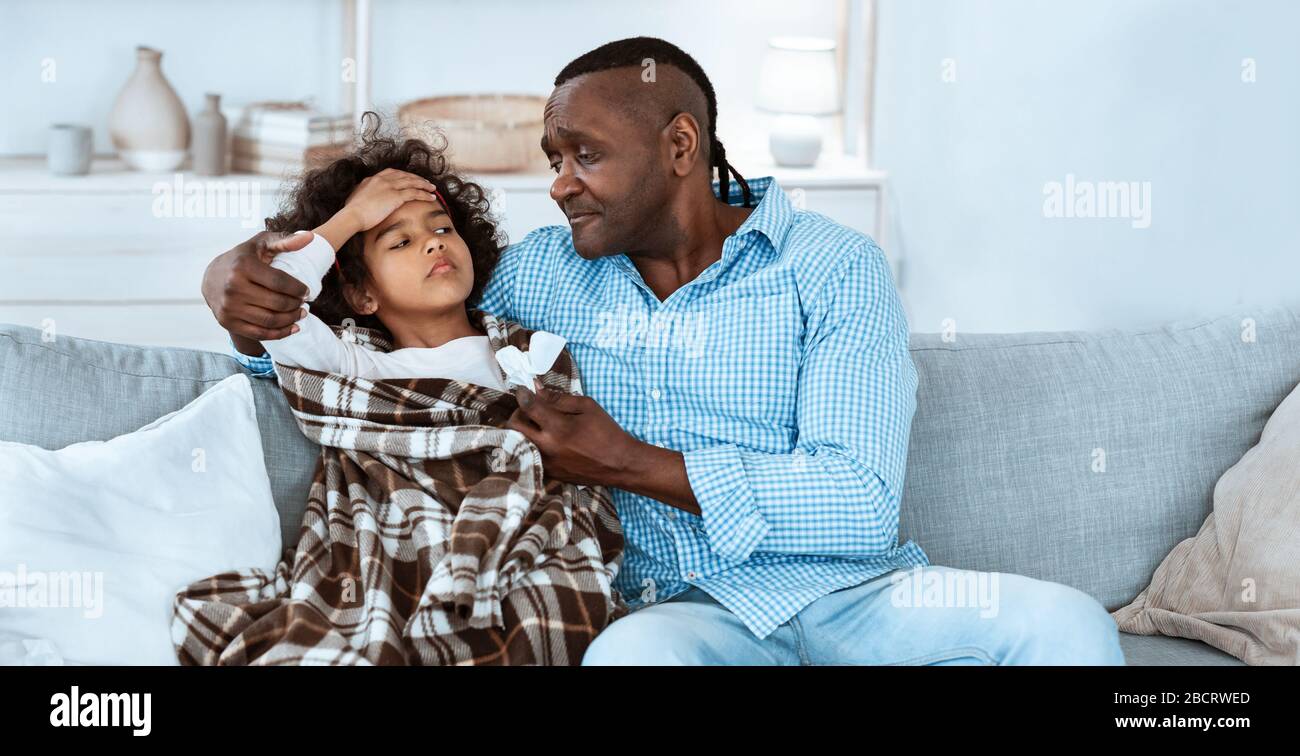 Rischio di virus. Ragazza afro-americana con febbre alta e il suo nonno turbato a casa, spazio vuoto. Panorama Foto Stock