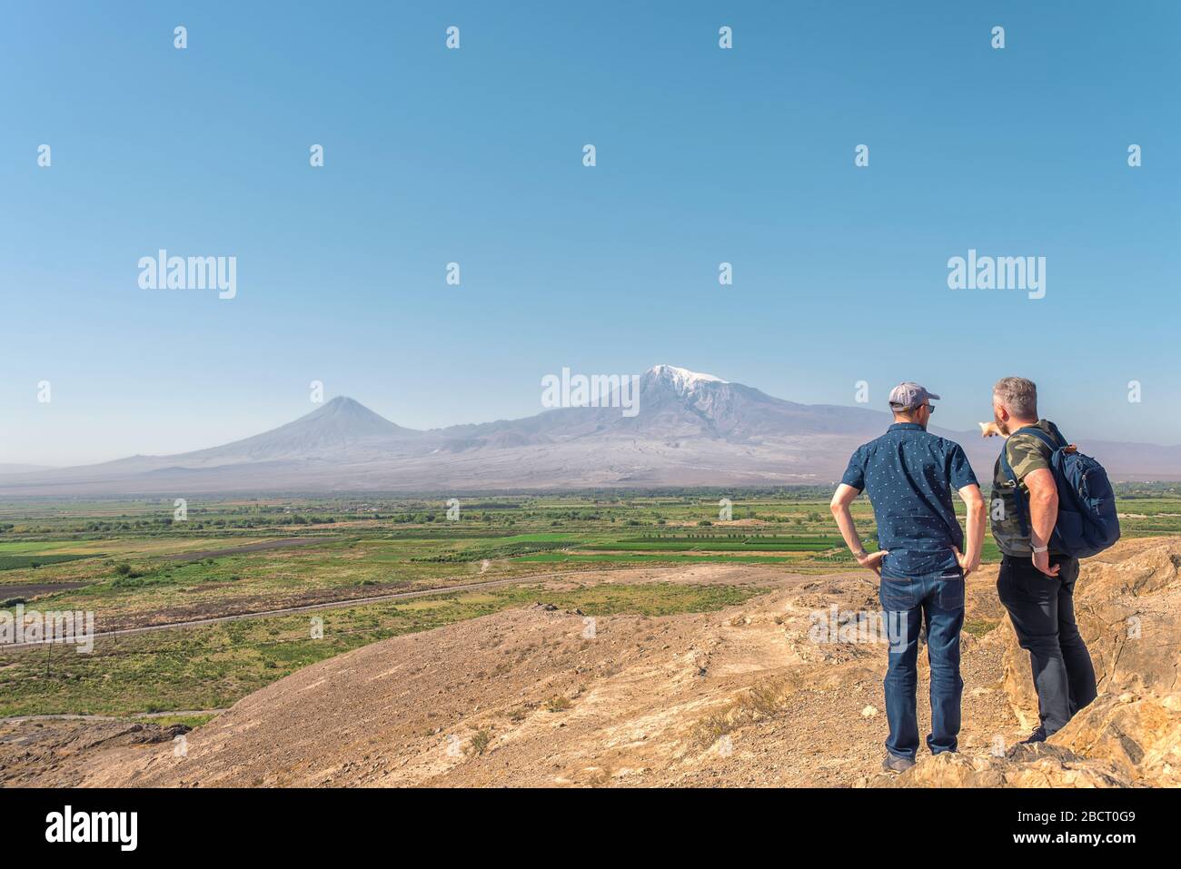 Panorama della montagna Ararat in Armenia con due maschi in cima ad una montagna e guardando ad una valle Foto Stock