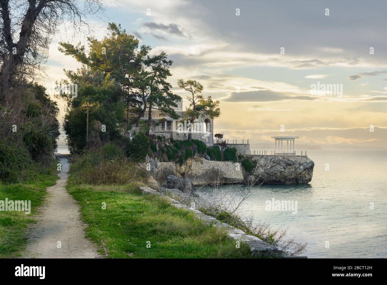 Un sentiero sul mare, che termina in una casa sul mare. Con nuvole e alberi e ferrovia Foto Stock