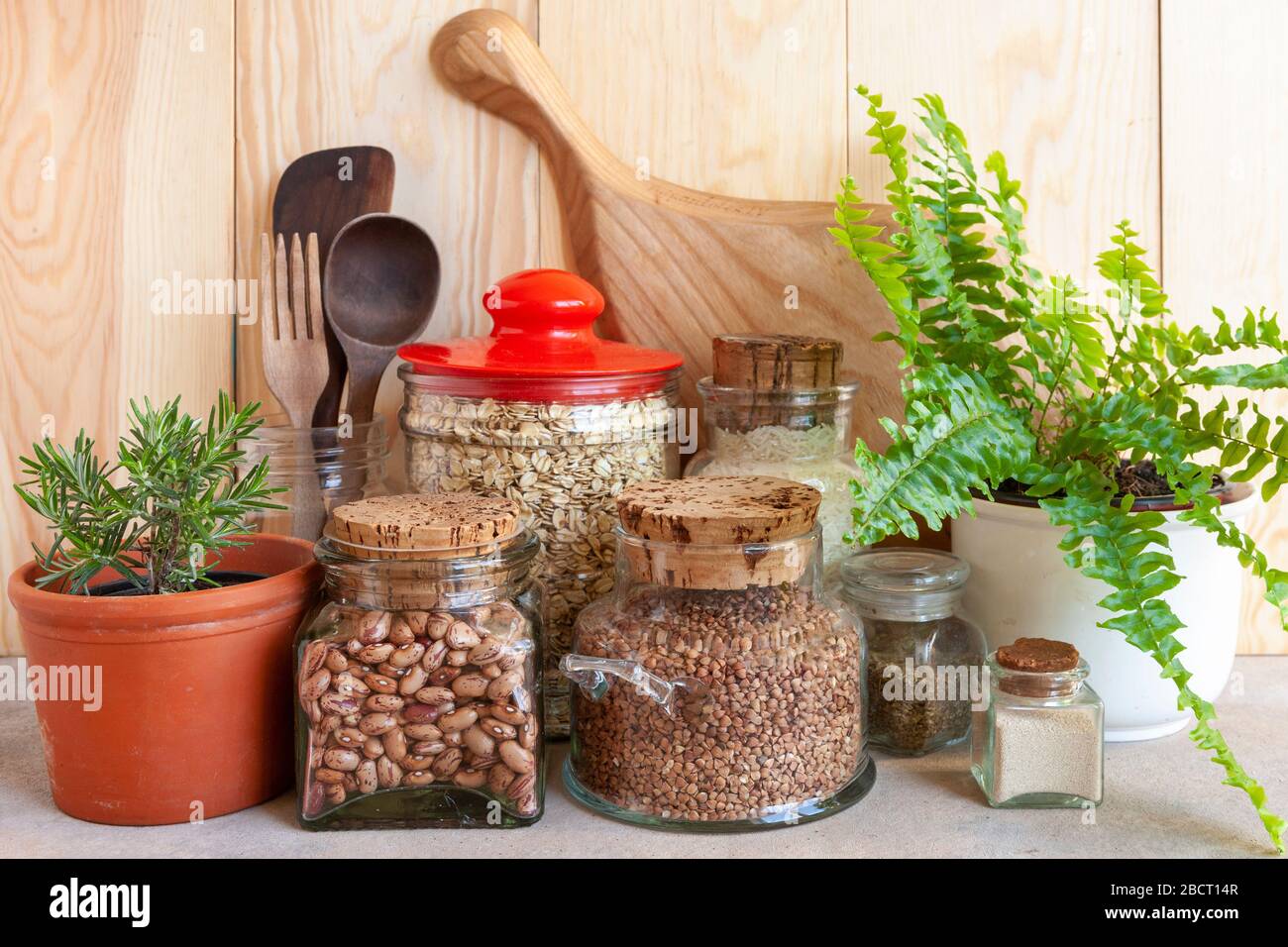 Vasi di cereali, utensili da cucina e piante domestiche. Ambiente sano, cucina confortevole, concetto di stile di vita sostenibile. Foto Stock