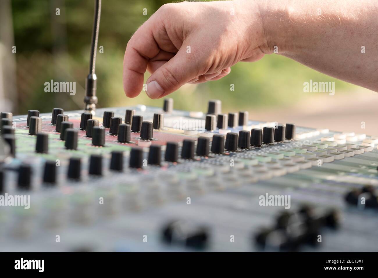 Primo piano di un ingegnere del suono alla scrivania di miscelazione all'aperto - potrebbe essere un matrimonio o un concerto Foto Stock