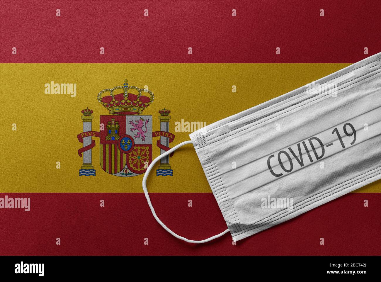 Una maschera chirurgica medica individuale sul fronte della bandiera nazionale spagnola. Maschera sanitaria. Protezione contro il virus COVID-19, influenza, SARS. Salva SPAI Foto Stock