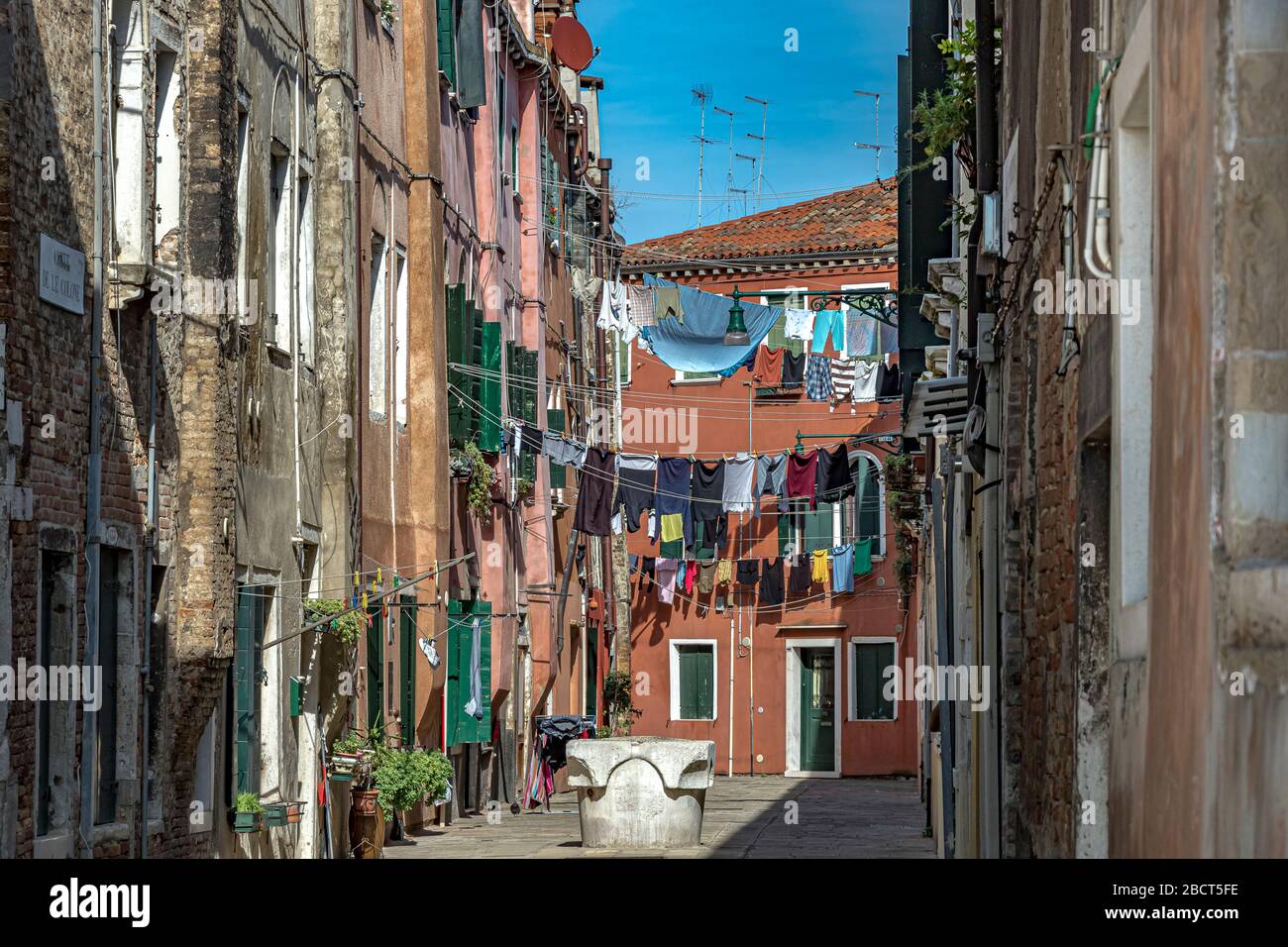 Lavaggio appeso ad asciugare su linea di lavaggio strung tra case in Corte Calle colonne un piccolo cortile a Venezia, Italia Foto Stock
