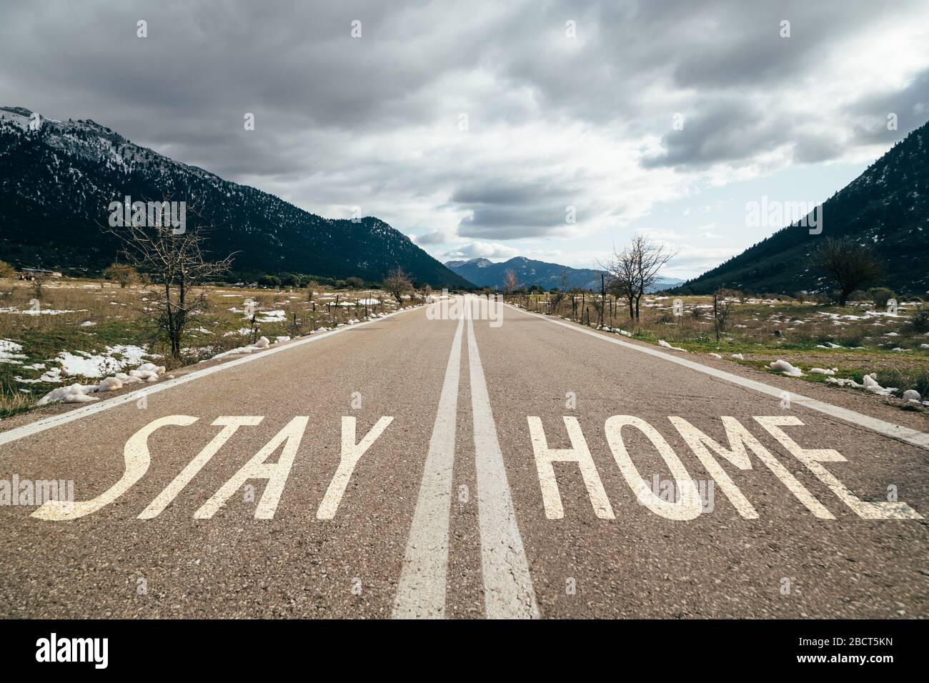 Segnale di avvertimento stradale rimanere a casa scritto su asfalto, campagna dei social media per la prevenzione del coronavirus. Rimani a casa concetto di sicurezza Foto Stock