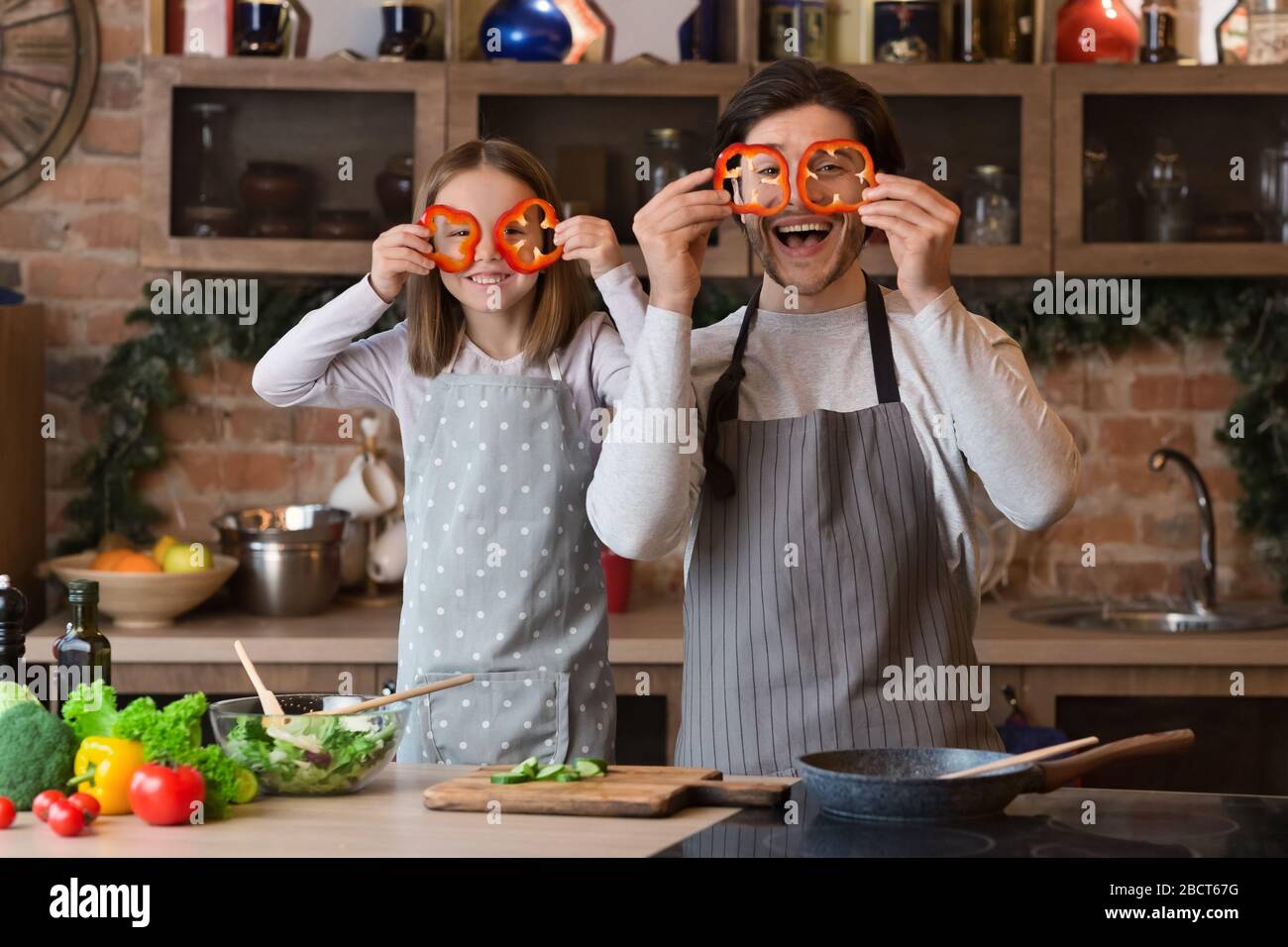 Padre e figlia giocano mentre cucinano, facendo i bicchieri di pepe dolce Foto Stock