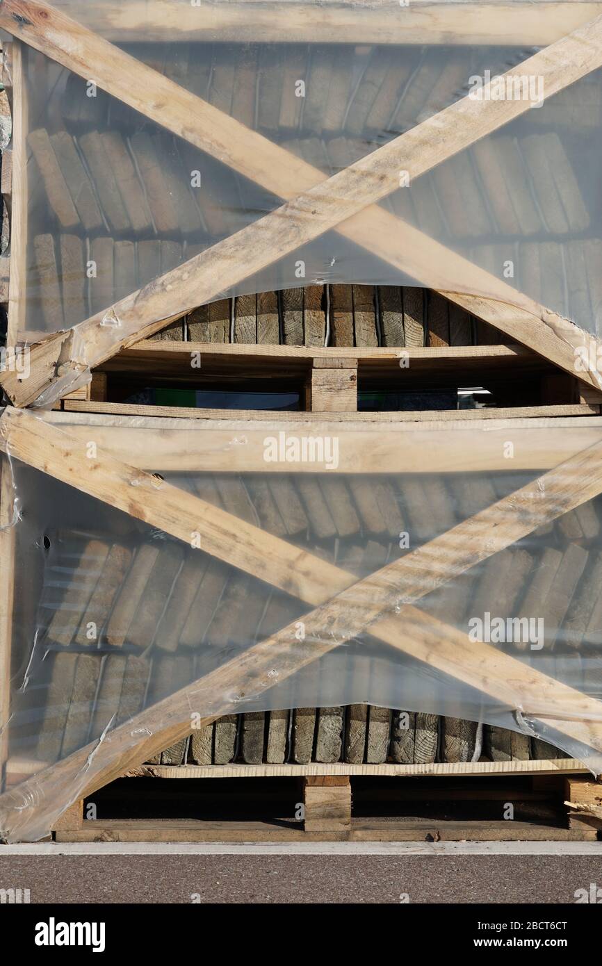 materiale da costruzione lastre di calcestruzzo graffate su pallet di legno, fissate sui lati da tavole incrociate e protette da spessa lamina di plastica Foto Stock