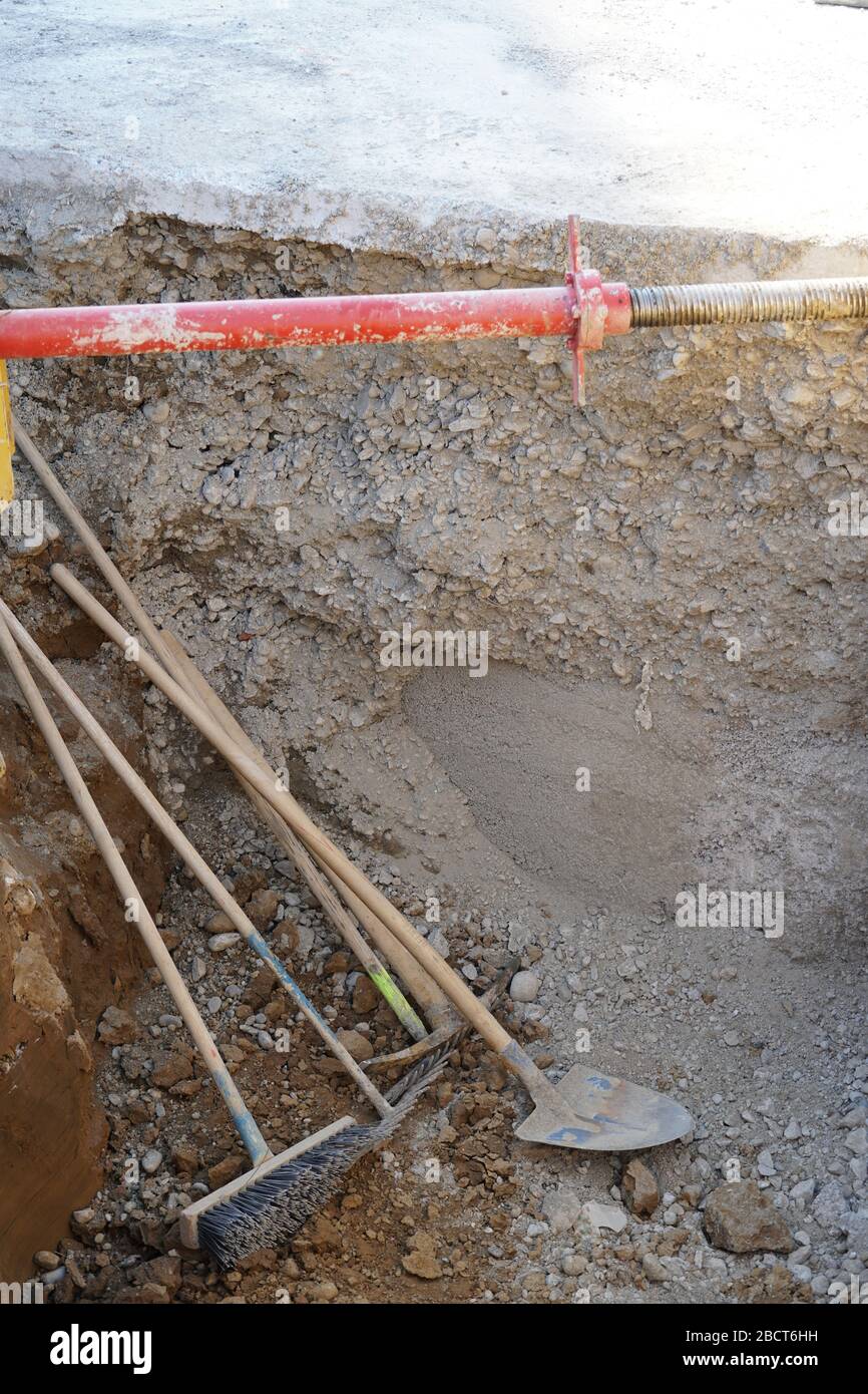 Attrezzatura accessoria lasciata in costruzione o buca di costruzione, una scopa una pala ed un mattock o un pickaxe. Questi strumenti non sono utilizzati solo in costrutto Foto Stock