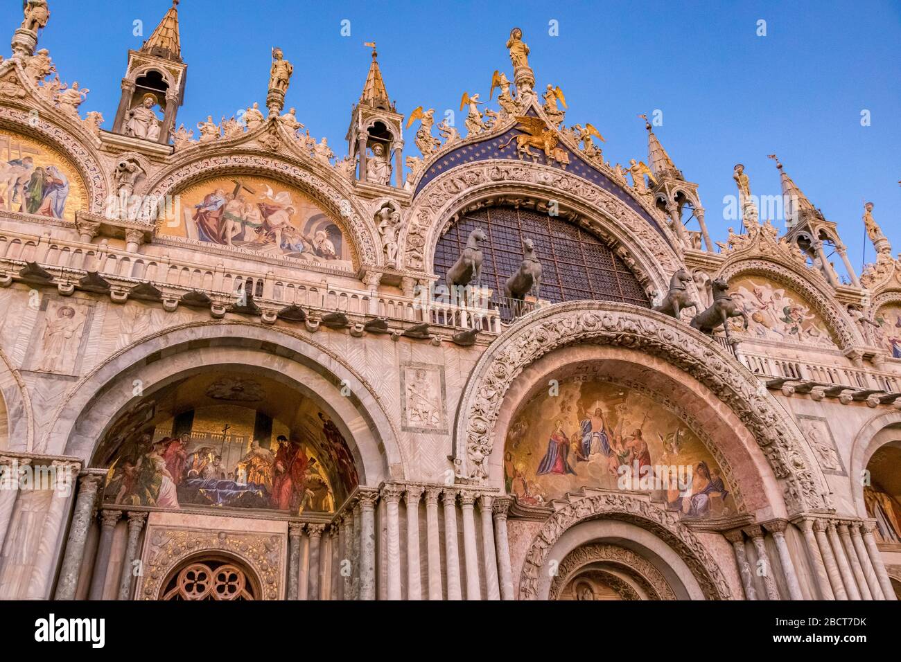Particolare della facciata ornata della Basilica di San Marco in prima serata che mostra i mosaici dorati sopra la porta centrale, Venezia, Italia Foto Stock
