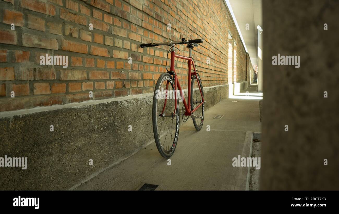 Bici a ingranaggi fissi in stile retrò rosso a singlespeed isolata su una parete in mattoni Foto Stock Bici a ingranaggi fissi in stile retrò rosso a singlespeed isolata su una parete in mattoni Foto Stock