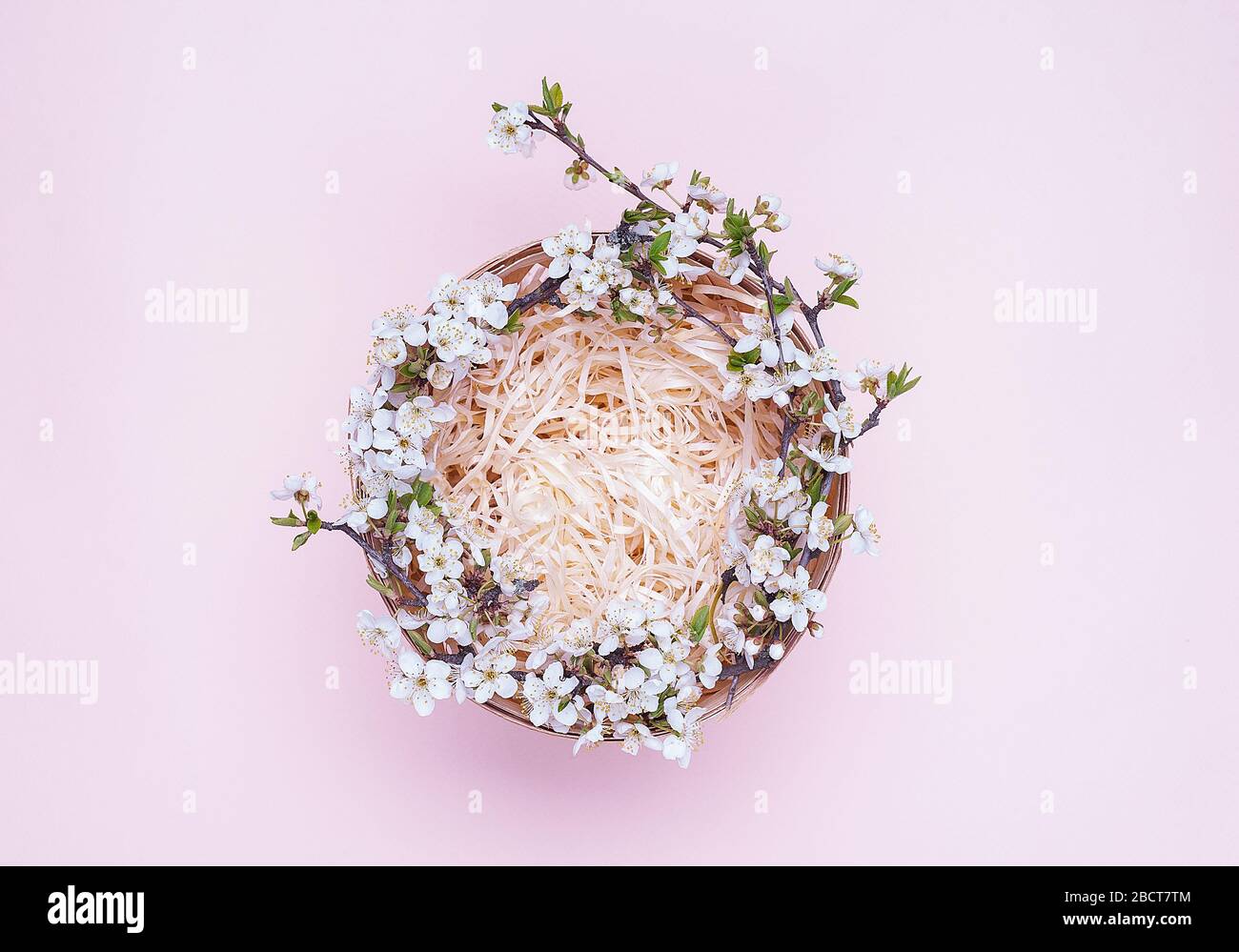 Cesto vuoto con una corona di fiori bianchi su sfondo rosa. Posizionare per il testo Flatley. Vista dall'alto. L'oggetto al centro della foto. Foto Stock