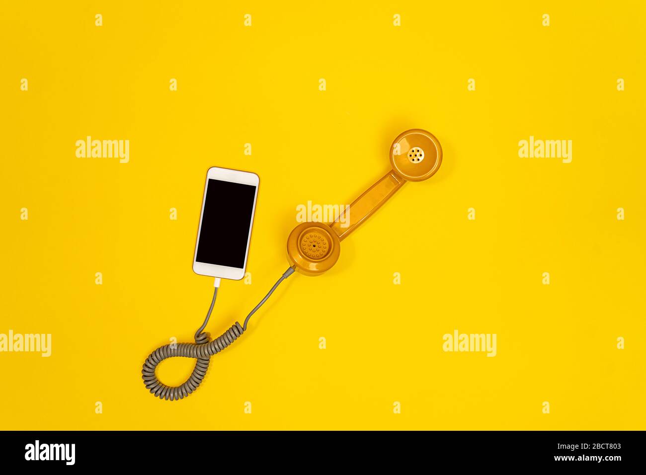 Telefono cellulare e telefono vecchio stile su sfondo giallo. Moderno stile retrò. Nuova vecchia tecnologia. Foto Stock