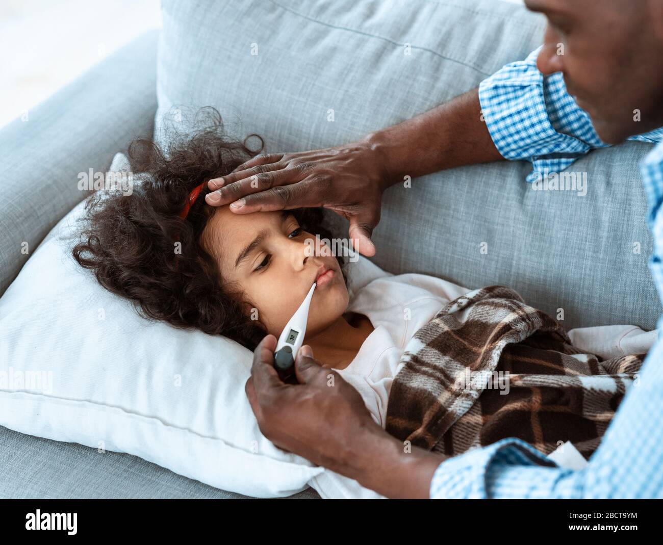 Allarme coronavirus. Ragazza African American che ha febbre e nonno preoccupato di nutrirla a casa Foto Stock