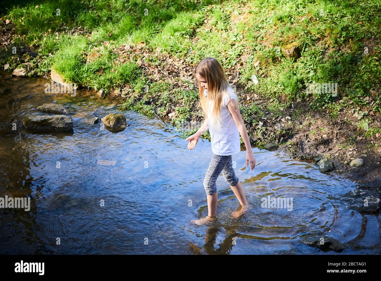 Bambino cute ragazza bionda coraggiosa che gioca nel torrente. Ragazza coraggiosa che cammina nel torrente della foresta ed esplora la natura. Divertimento estivo per i bambini. Bambini estate Foto Stock