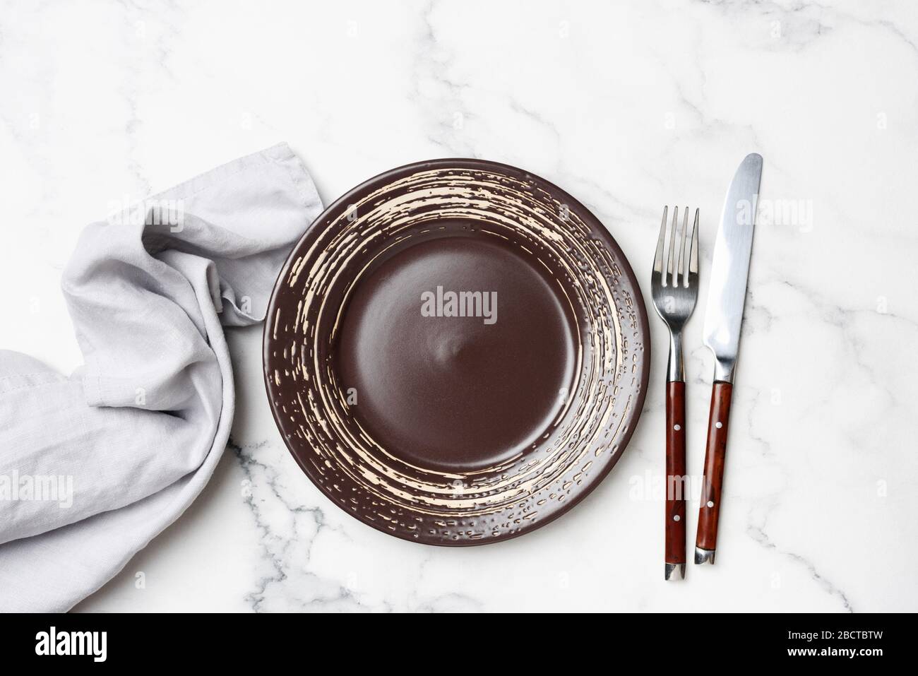 Tabella impostazione piastra vuota e oggetti da tavola su sfondo tabella di marmo bianco. Vista superiore Copia spazio per disegno o testo Foto Stock