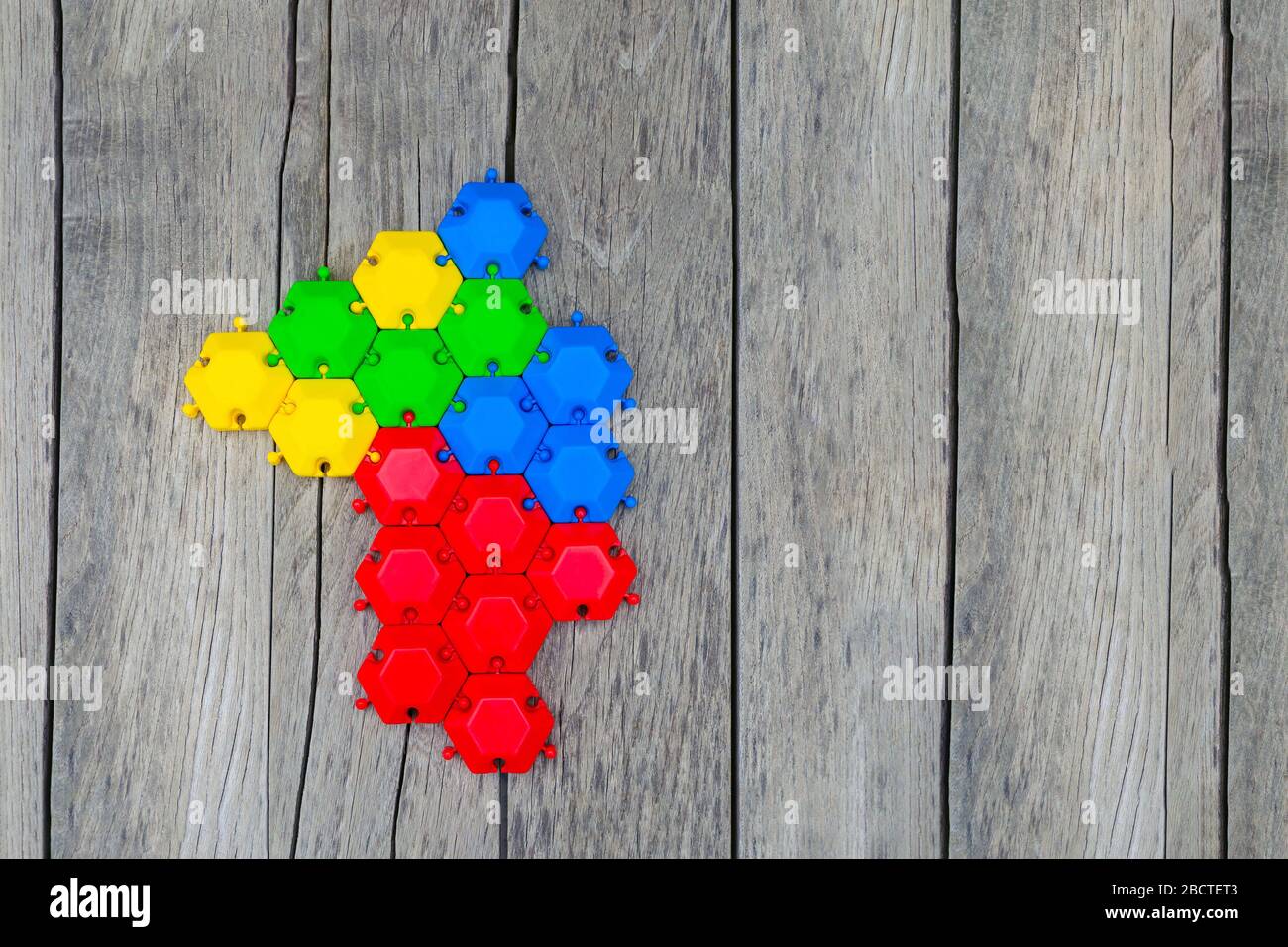 puzzle di gioco di esagoni multicolore assemblati in uno. concetto di unità, supporto, relazioni forti. sfondo in legno. spazio di copia Foto Stock