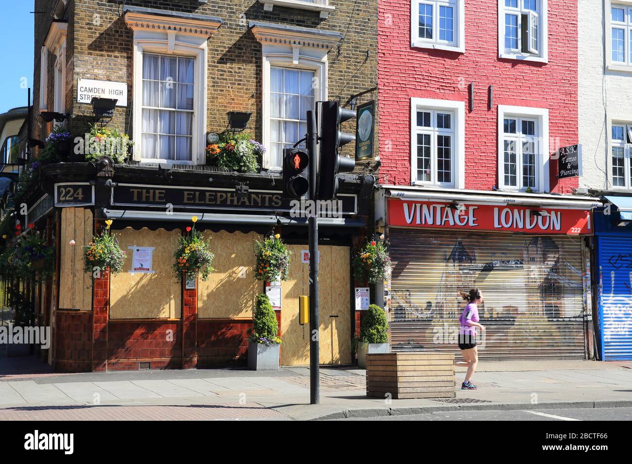Lone jogger passando negozi e pub chiusi sulla colorata Camden High Street sotto la pandemia di coronavirus, a nord di Londra, Regno Unito Foto Stock