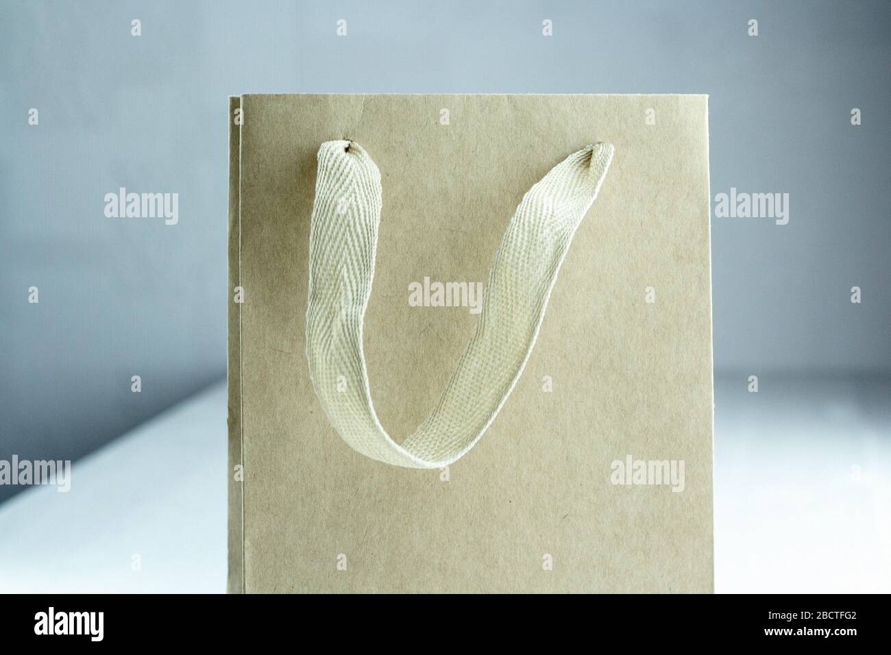 Piccolo sacchetto di carta artigianale usa e getta per il prelievo su tavolo bianco all'interno. Modello di imballaggio mock up. Manico in materiali naturali. Parte di Foto Stock