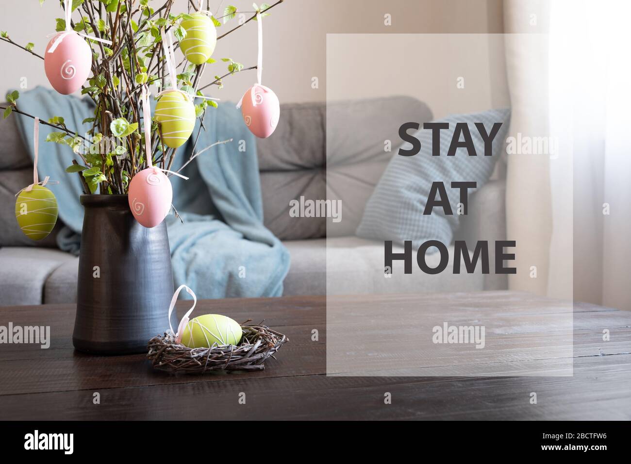 Casa di Pasqua interiore. Vaso con rami di betulla fresco decorato uova e nido. Testo - soggiorno a casa. Autoisolamento. COVID-19. Quarantena. Foto Stock