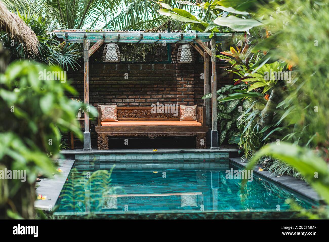 Piccola piscina privata nella casa di Bali. Verdi piante tropicali intorno, divano di legno. Villa nella giungla. Foto Stock