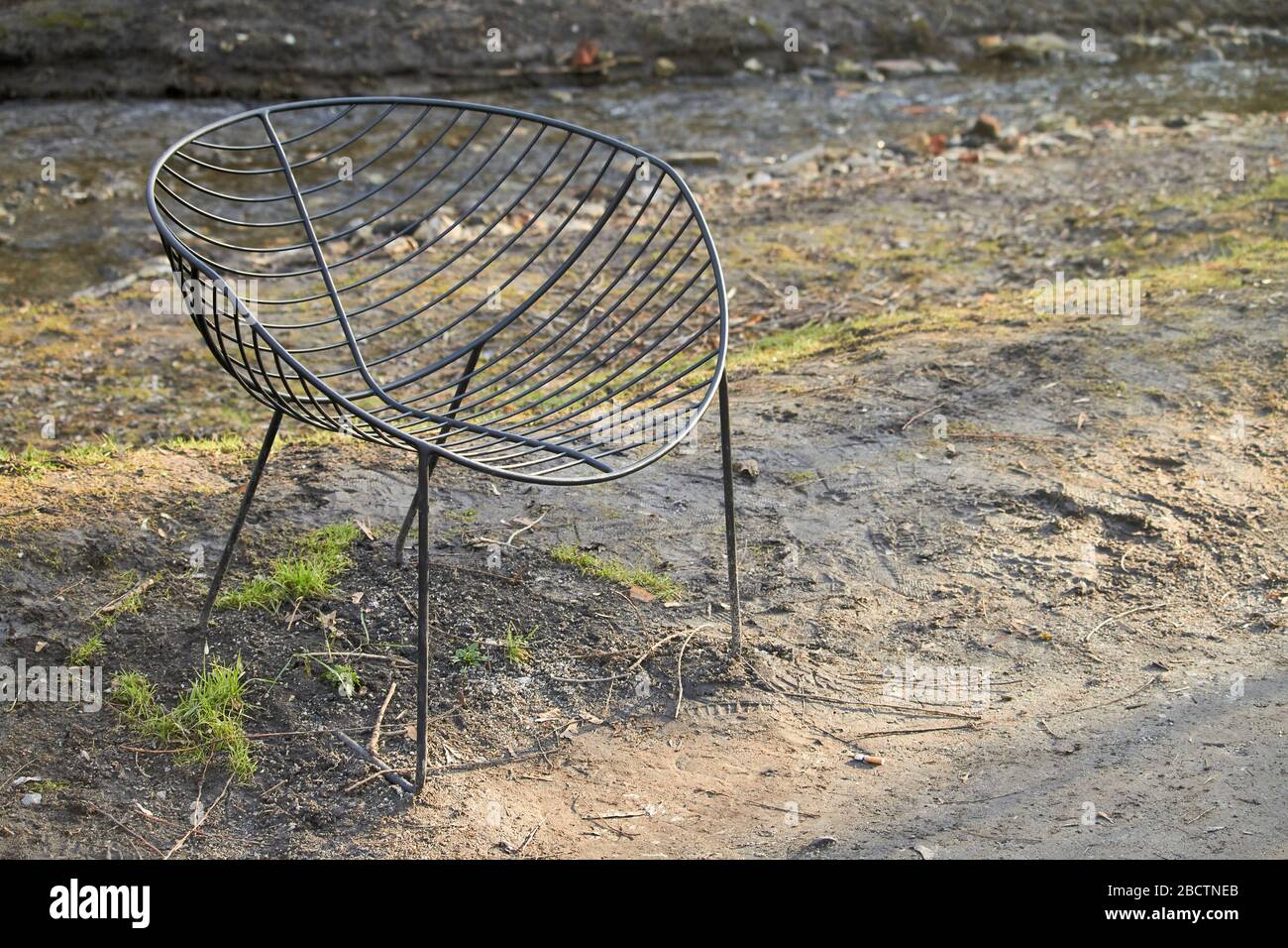 Poltrona in metallo in un parco cittadino. Mobili da giardino, poltrona in filo nero su un prato verde. Foto Stock