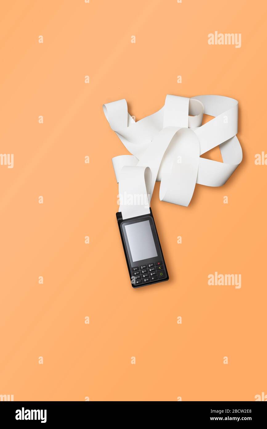 TERMINALE per carta di credito wireless POS per pagamenti e nastro di contanti a rotolo lungo su sfondo arancione. Foto Stock