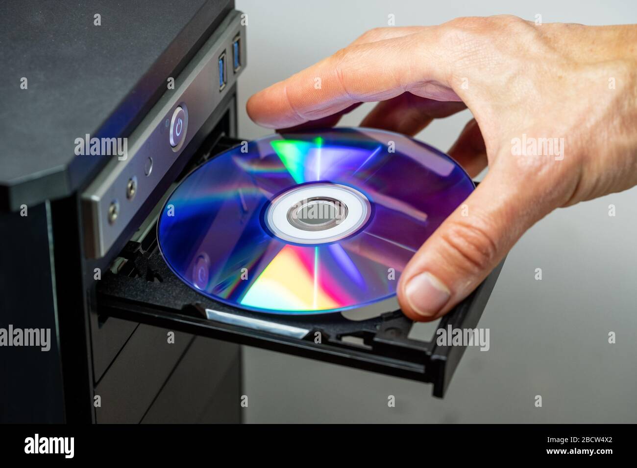 Mano che inserisce il DVD in un computer. Primo piano. Foto Stock