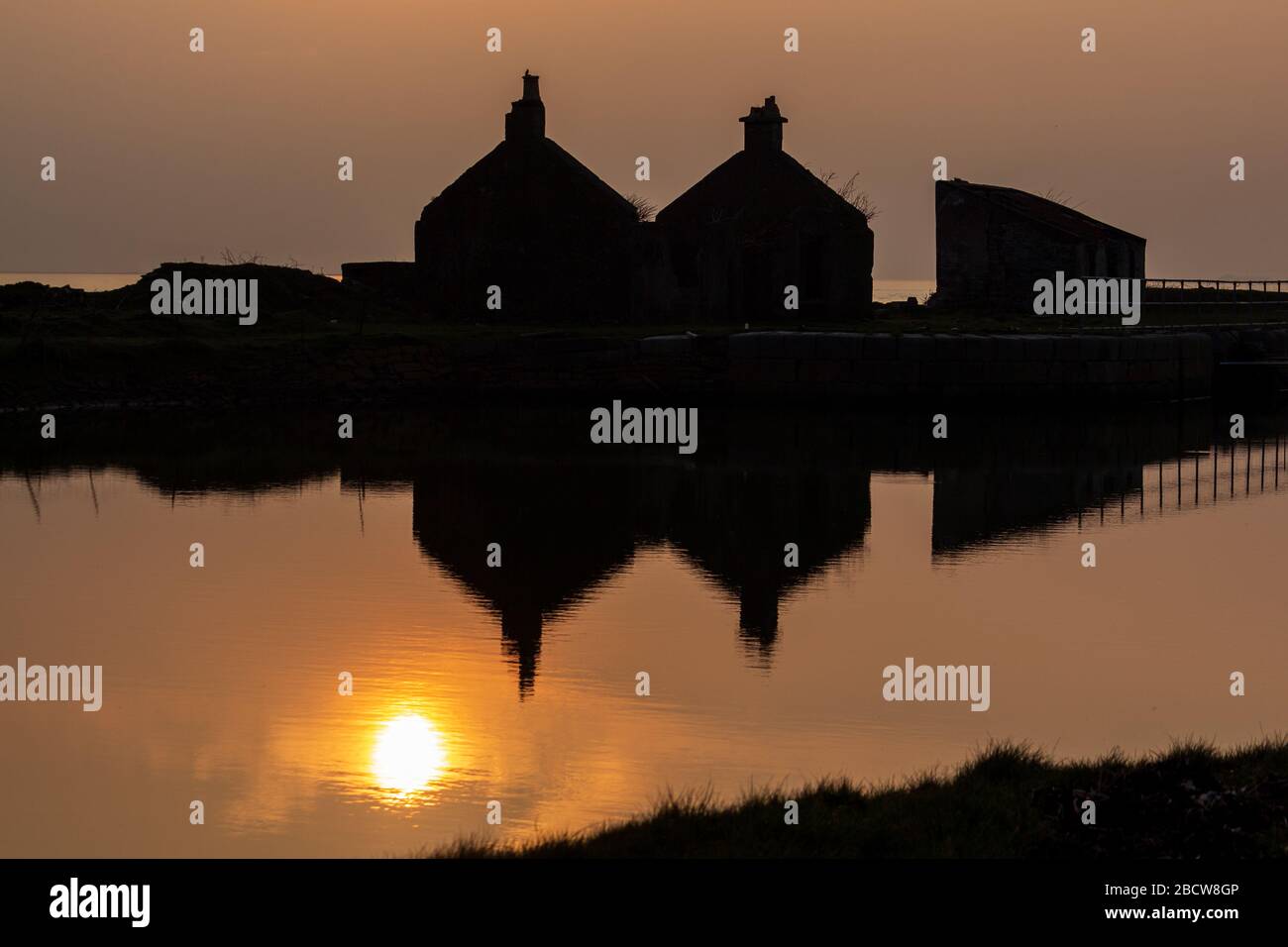 Riflessi del Tramonto ed edifici dalle silhouette in acque calme Foto Stock