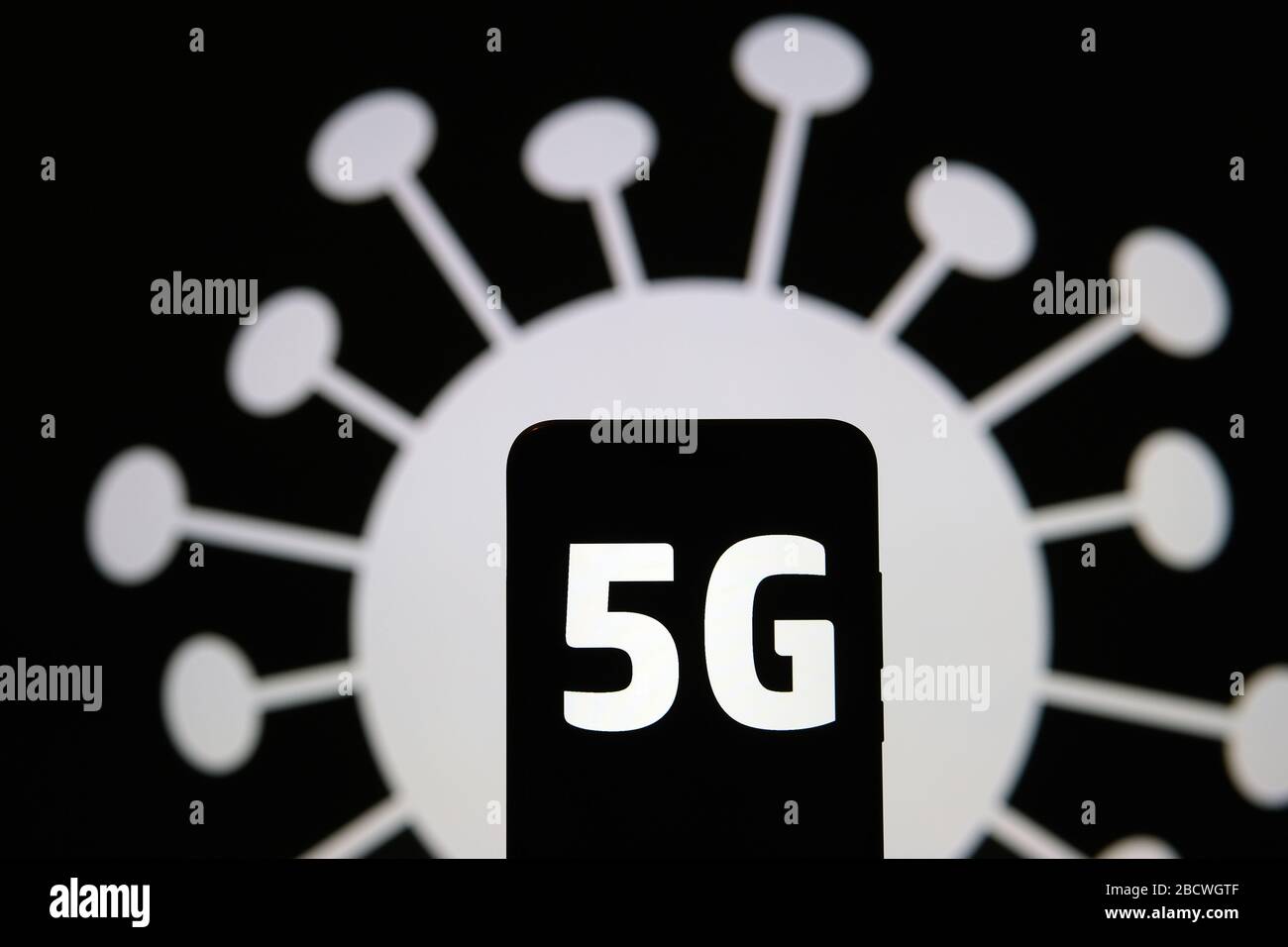 Radiazione 5G a forma di COVID-19. Le lettere 5G sulla silhouette dello smartphone tengono in mano e l'immagine del coronavirus sullo sfondo. Foto vera, non un m Foto Stock