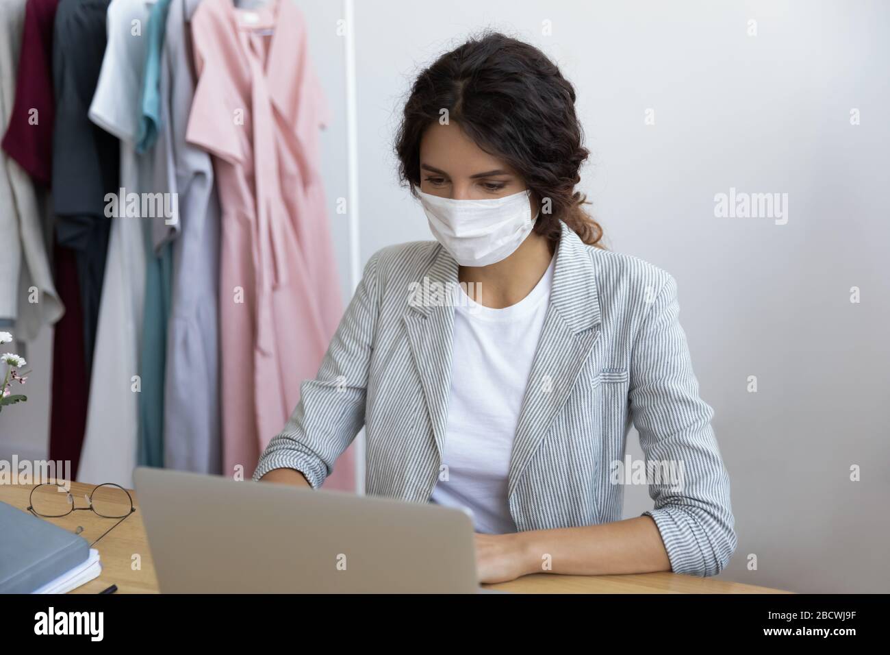 Giovane uomo d'affari sano in maschera che lavora al computer in ufficio. Foto Stock