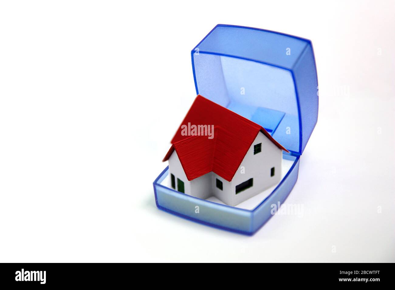 Immagine concettuale di una piccola casa con un tetto rosso nascosto in una scatola di gioiello da offrire come un regalo Foto Stock