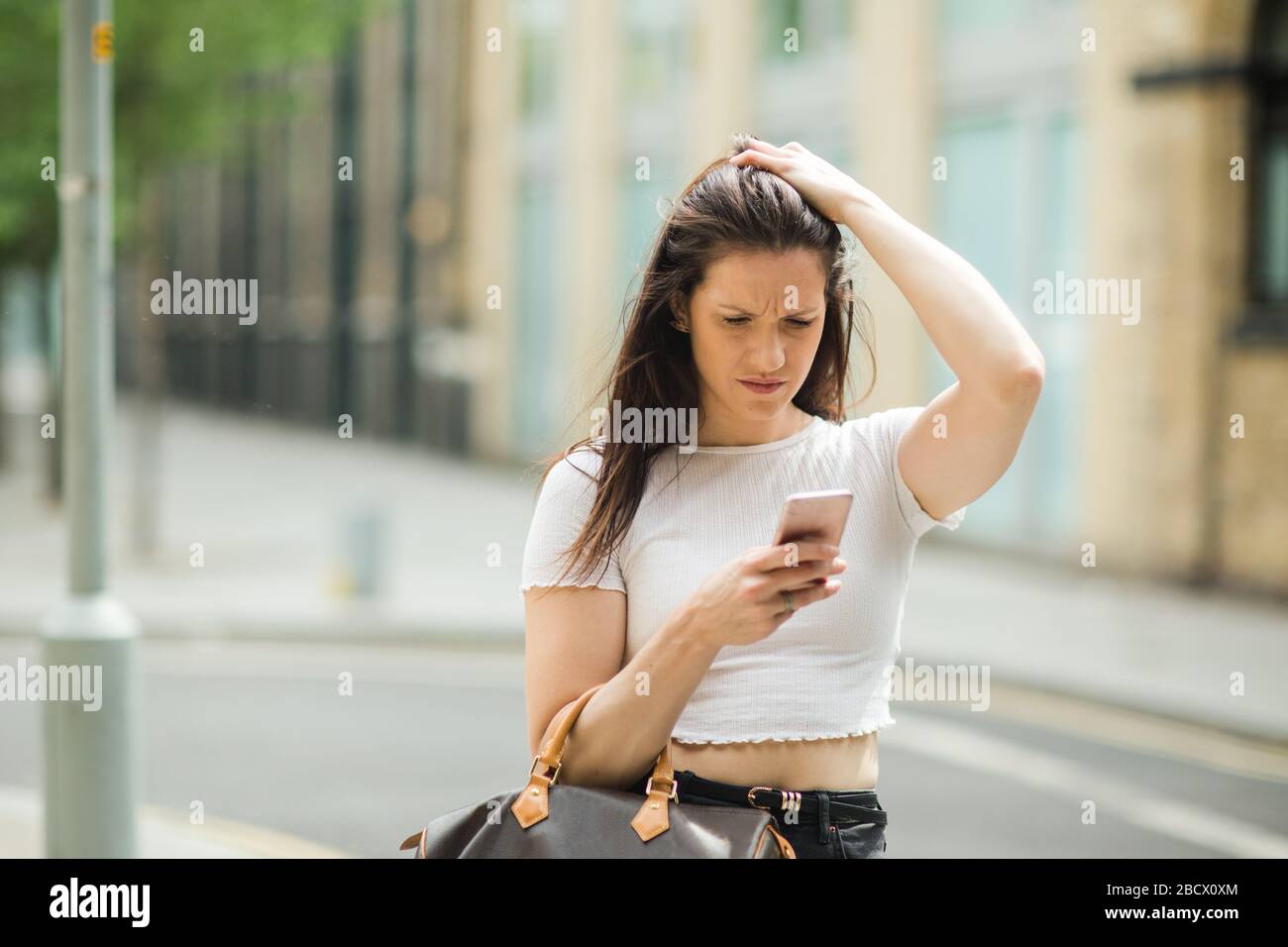 giovane donna in strada che legge un messaggio di testo. Foto Stock
