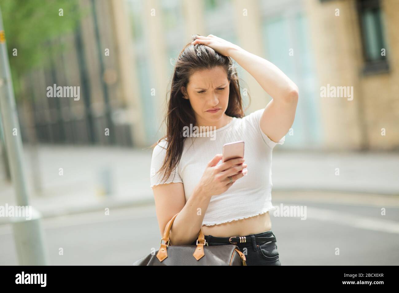giovane donna che guarda confusa con il suo telefono cellulare Foto Stock