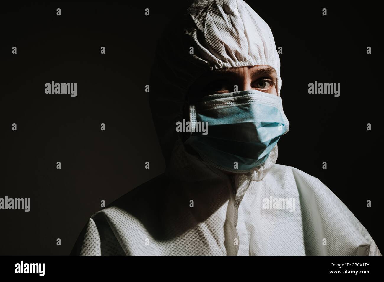 Medico femmina triste e grave con maschera e schermo per la protezione del coronavirus covid-19 su sfondo nero Foto Stock