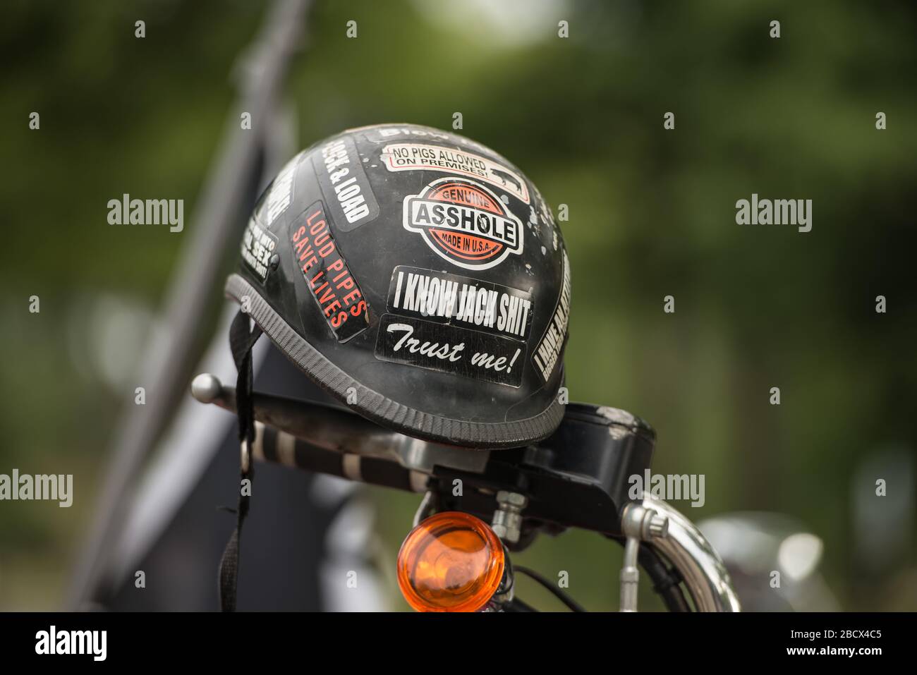 Casco per moto coperto da emblemi, appeso su una moto a un rally Thunder. Foto Stock