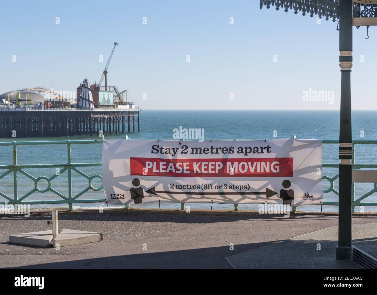 Durante COVID-19. 'Stay 2 metri di distanza' di fronte al molo del Palazzo di Brighton Foto Stock