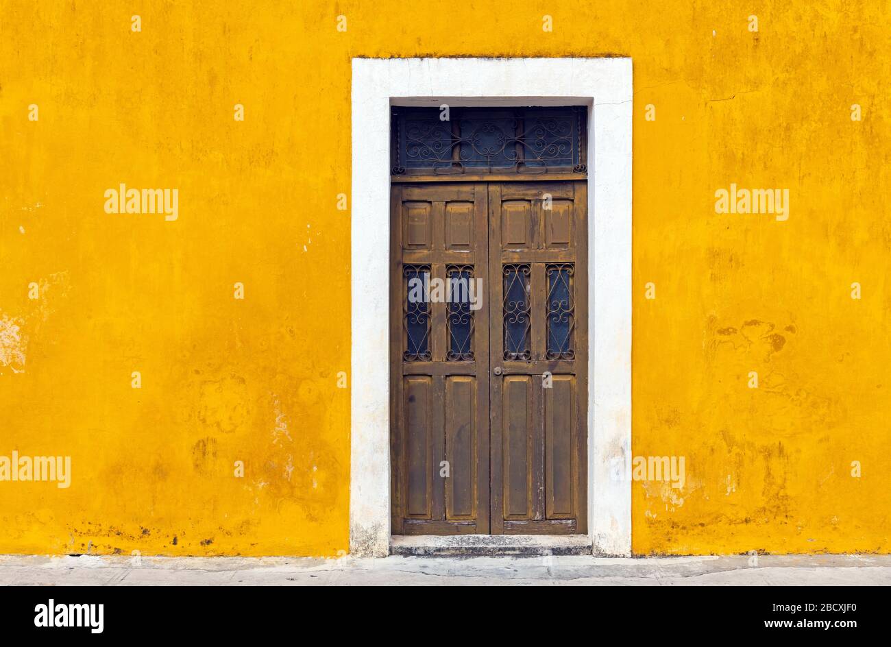 Parete gialla facciata e porta nel centro della città di Izamal, penisola dello Yucatan, Messico. Foto Stock