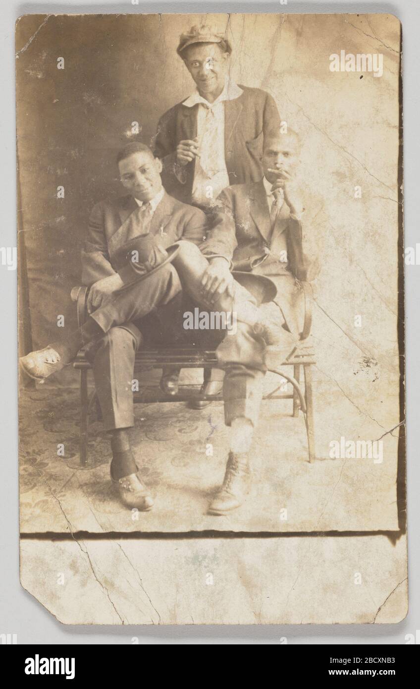 Cartolina fotografica di tre uomini non identificati. Una cartolina fotografica di tre uomini. Gli uomini sembrano essere posti su uno sfondo in studio fotografico. Due uomini sono seduti su una panchina e il terzo uomo è dietro di loro. Gli uomini indossano abiti e hanno cappelli. Cartolina fotografica di tre uomini non identificati Foto Stock Cartolina fotografica di tre uomini non identificati. Una cartolina fotografica di tre uomini. Gli uomini sembrano essere posti su uno sfondo in studio fotografico. Due uomini sono seduti su una panchina e il terzo uomo è dietro di loro. Gli uomini indossano abiti e hanno cappelli. Cartolina fotografica di tre uomini non identificati Foto Stock