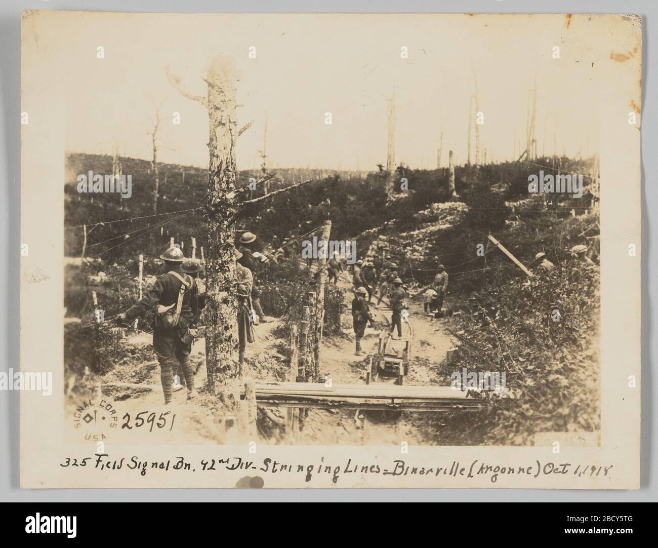 325 segnale di campo BN 92nd Div Stringing Lines Binarville Argonne 1 ottobre 1918. In questa fotografia, i soldati stanno stringendo linee lungo gli alberi aridi attraverso il terreno collinare. Un asse di legno collega due scogliere collinari mentre i soldati lavorano sotto. C'è un carro incustodito nella pulizia dello sporco sotto il piano di legno. 325 segnale di campo BN 92nd Div Stringing Lines Binarville Argonne 1 ottobre 1918 Foto Stock 325 segnale di campo BN 92nd Div Stringing Lines Binarville Argonne 1 ottobre 1918. In questa fotografia, i soldati stanno stringendo linee lungo gli alberi aridi attraverso il terreno collinare. Un asse di legno collega due scogliere collinari mentre i soldati lavorano sotto. C'è un carro incustodito nella pulizia dello sporco sotto il piano di legno. 325 segnale di campo BN 92nd Div Stringing Lines Binarville Argonne 1 ottobre 1918 Foto Stock