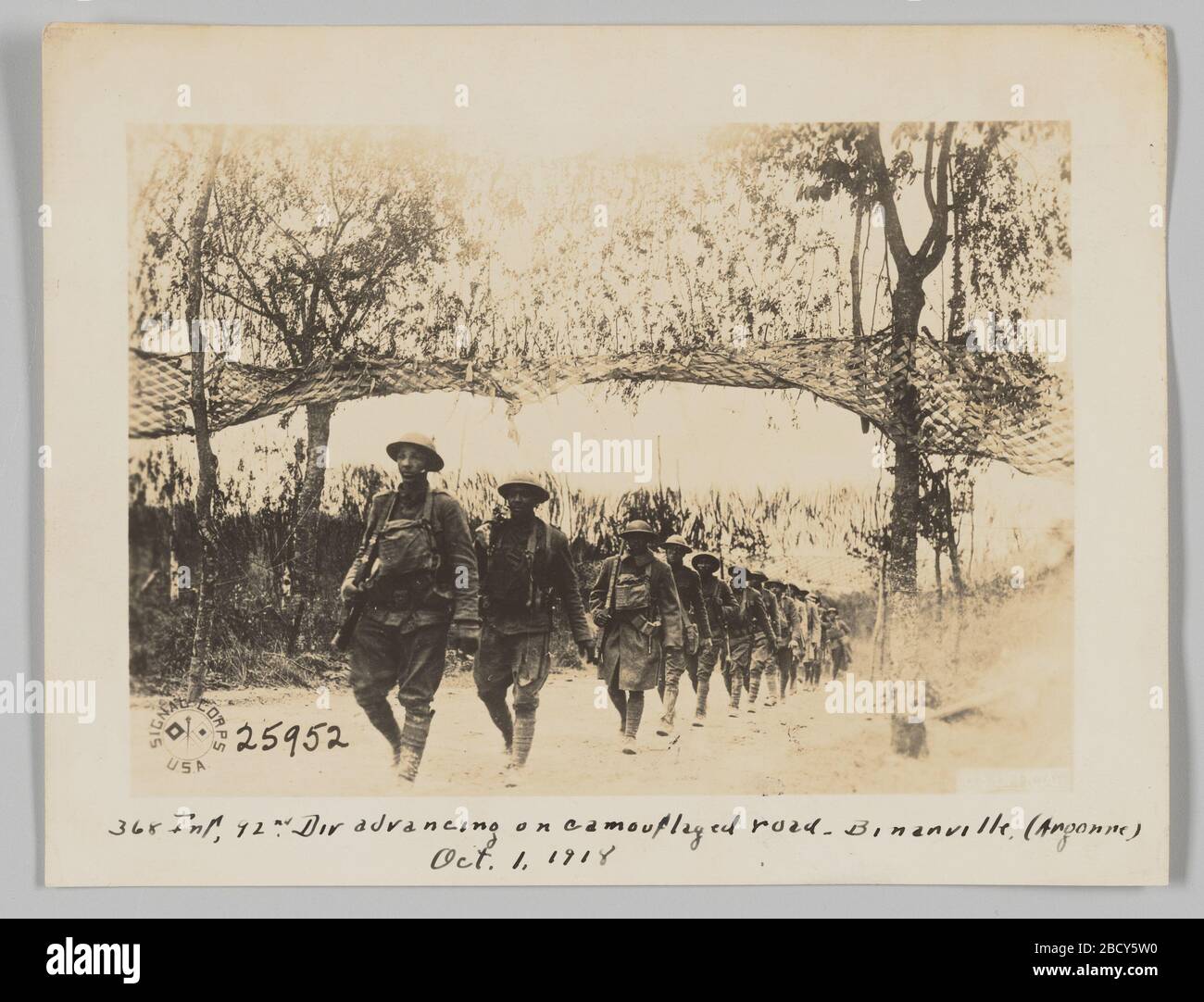 368 INF 92nd Div avanzando su strada camuffata Binarville Argonne 1 ottobre 1918. Questa fotografia raffigura soldati che camminano lungo una strada in una linea a file singolo. I soldati indossano caschi e fucili. Alberi fiancheggiano entrambi i lati della strada. Due reti sono sospese negli alberi e coprono la strada dall'alto. 368 INF 92nd Div avanzando su strada camuffata Binarville Argonne 1 ottobre 1918 Foto Stock 368 INF 92nd Div avanzando su strada camuffata Binarville Argonne 1 ottobre 1918. Questa fotografia raffigura soldati che camminano lungo una strada in una linea a file singolo. I soldati indossano caschi e fucili. Alberi fiancheggiano entrambi i lati della strada. Due reti sono sospese negli alberi e coprono la strada dall'alto. 368 INF 92nd Div avanzando su strada camuffata Binarville Argonne 1 ottobre 1918 Foto Stock
