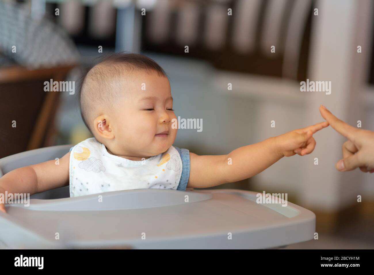 Asiatica bella ragazza del bambino con giocare con i suoi genitori. Tocca il dito con la mamma Foto Stock