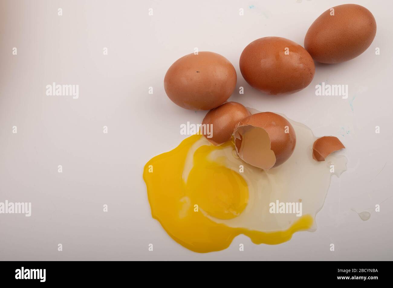 Un uovo di pollo spezzato e uova sparse su sfondo bianco. Primo piano Foto Stock