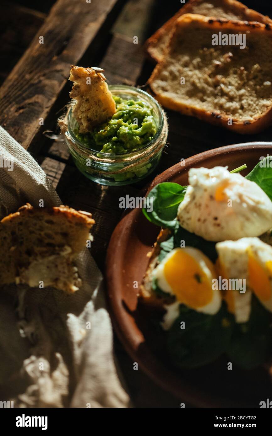 Colazione appetitosa uova sode, toast, formaggio e funghi in un piatto di argilla su un fondo di legno. Uovo medio cotto. Foto Stock