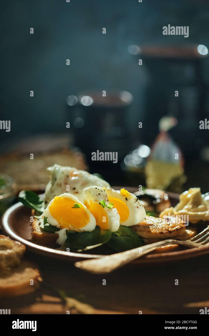 Colazione appetitosa uova sode, toast, formaggio e funghi in un piatto di argilla su un fondo di legno. Uovo medio cotto. Foto Stock