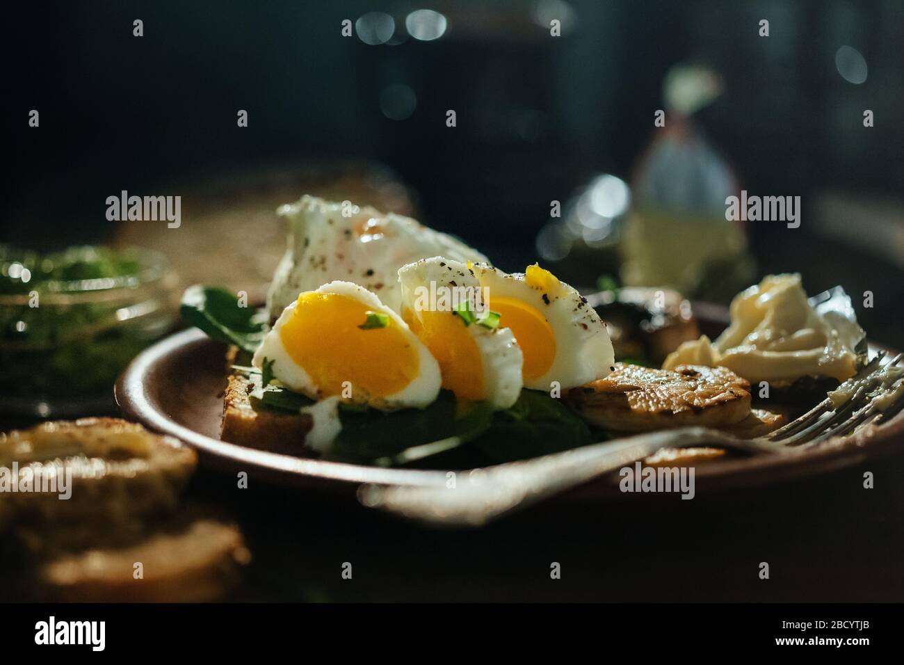 Colazione appetitosa uova sode, toast, formaggio e funghi in un piatto di argilla su un fondo di legno. Uovo medio cotto. Foto Stock