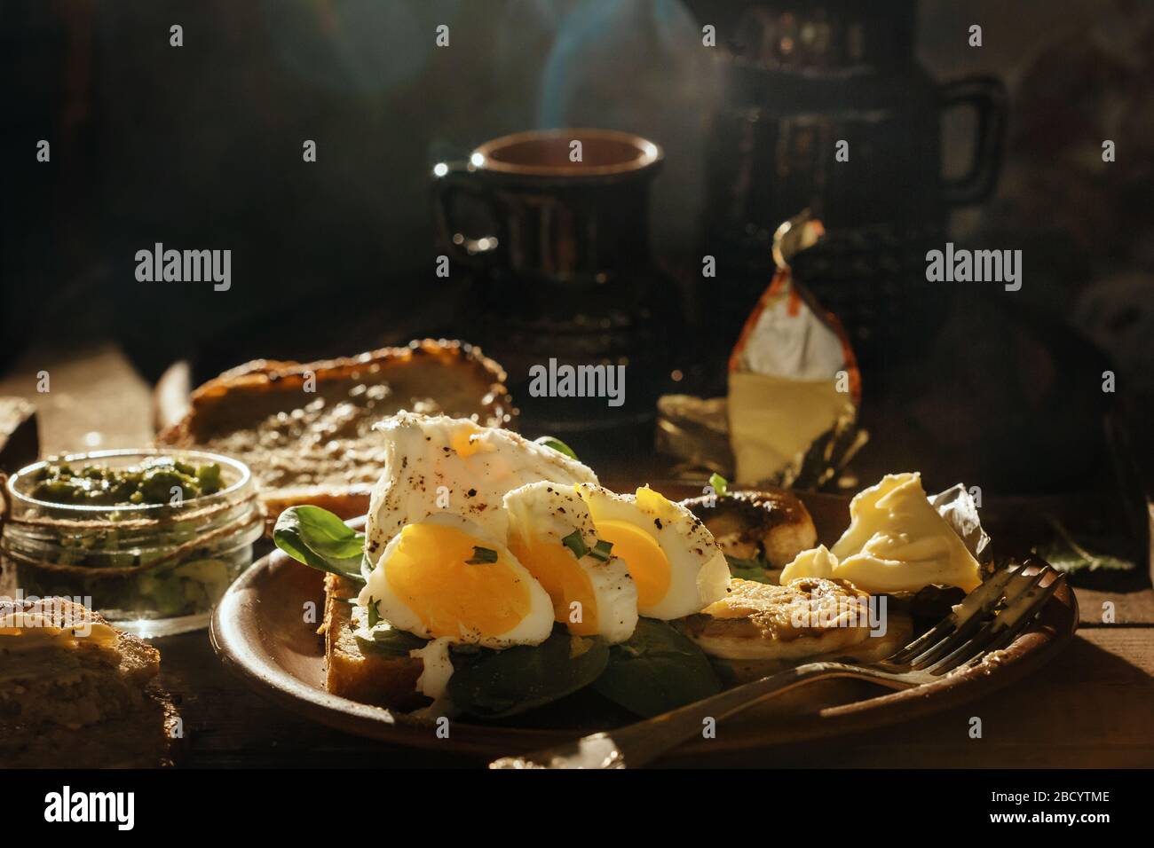 Colazione appetitosa uova sode, toast, formaggio e funghi in un piatto di argilla su un fondo di legno. Uovo medio cotto. Foto Stock