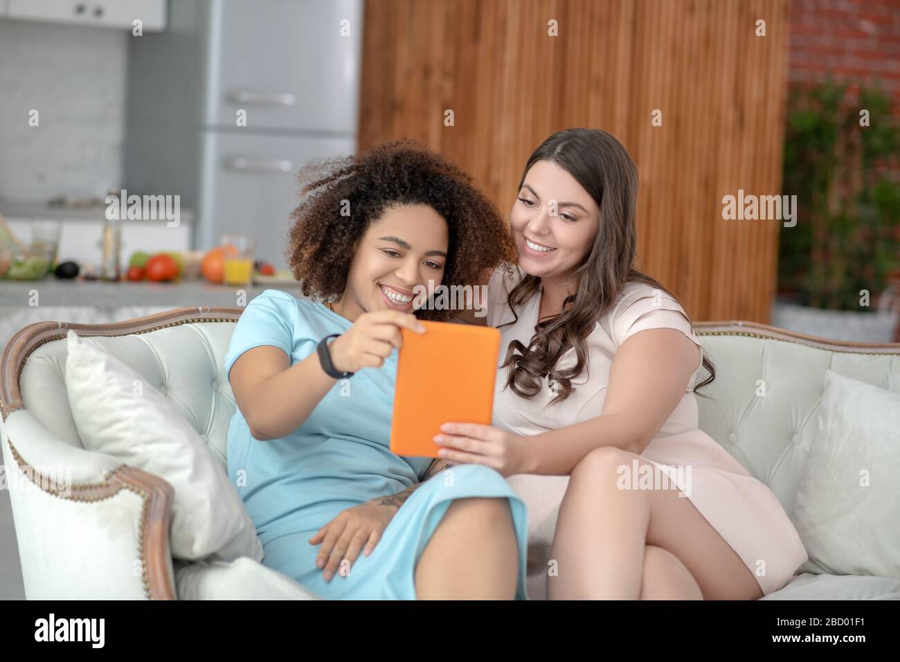 Due giovani girlfriends che prendono selfie sul tablet a casa. Foto Stock