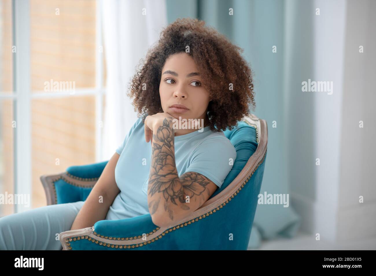 Giovane donna annoiato a casa in una poltrona. Foto Stock