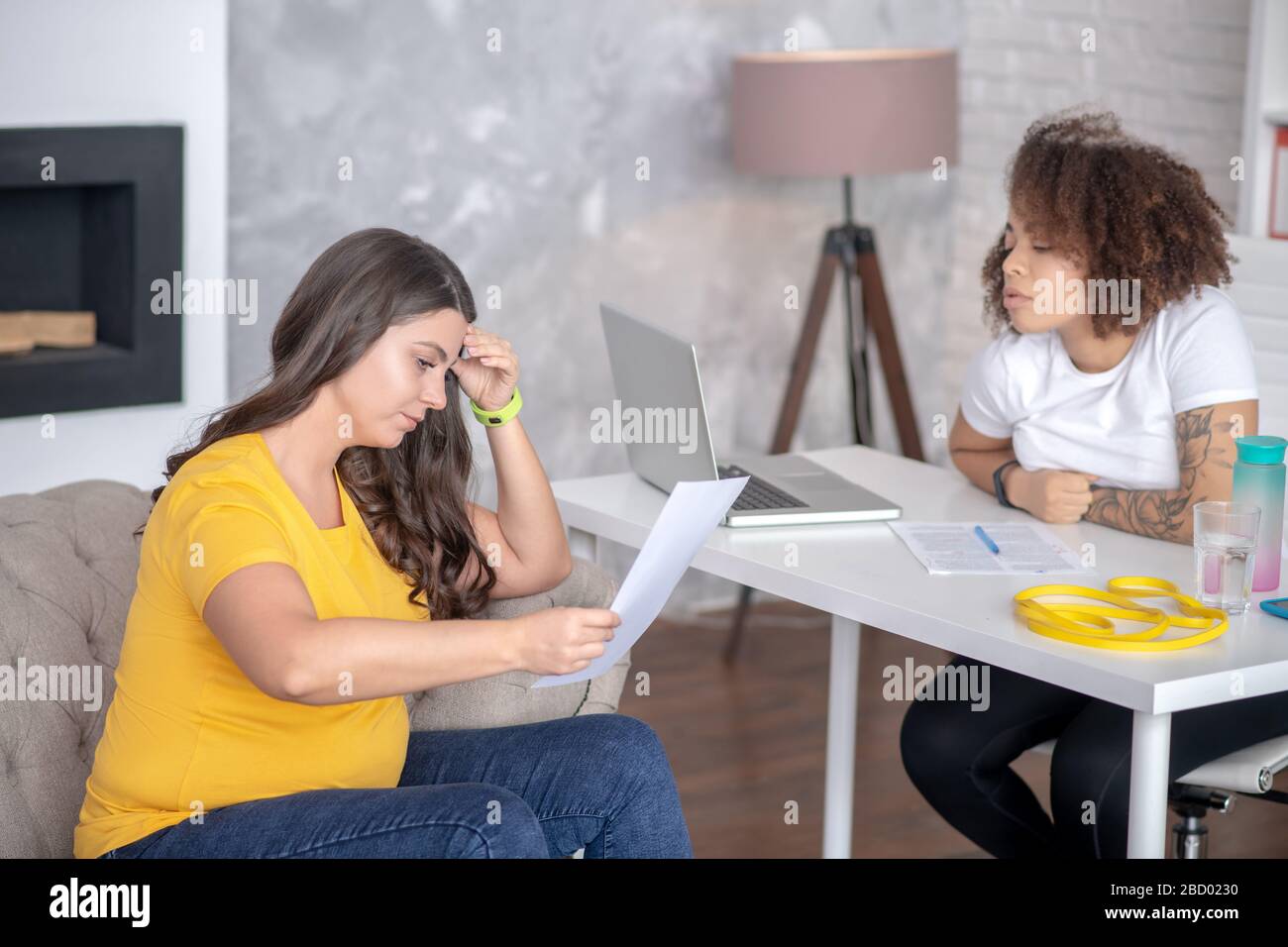 Donna in sovrappeso giovane lettura di un foglio di assegnazione, consulente nelle vicinanze. Foto Stock