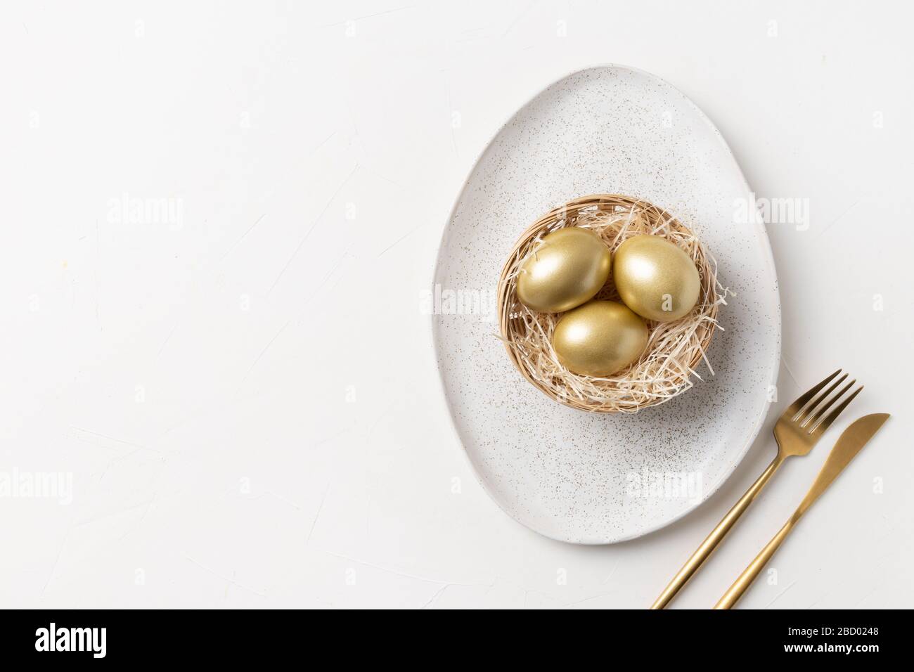 Pasqua elegante tavolo con uova dorate in nido su tavolo bianco. Vista dall'alto. Spazio per il testo. Foto Stock