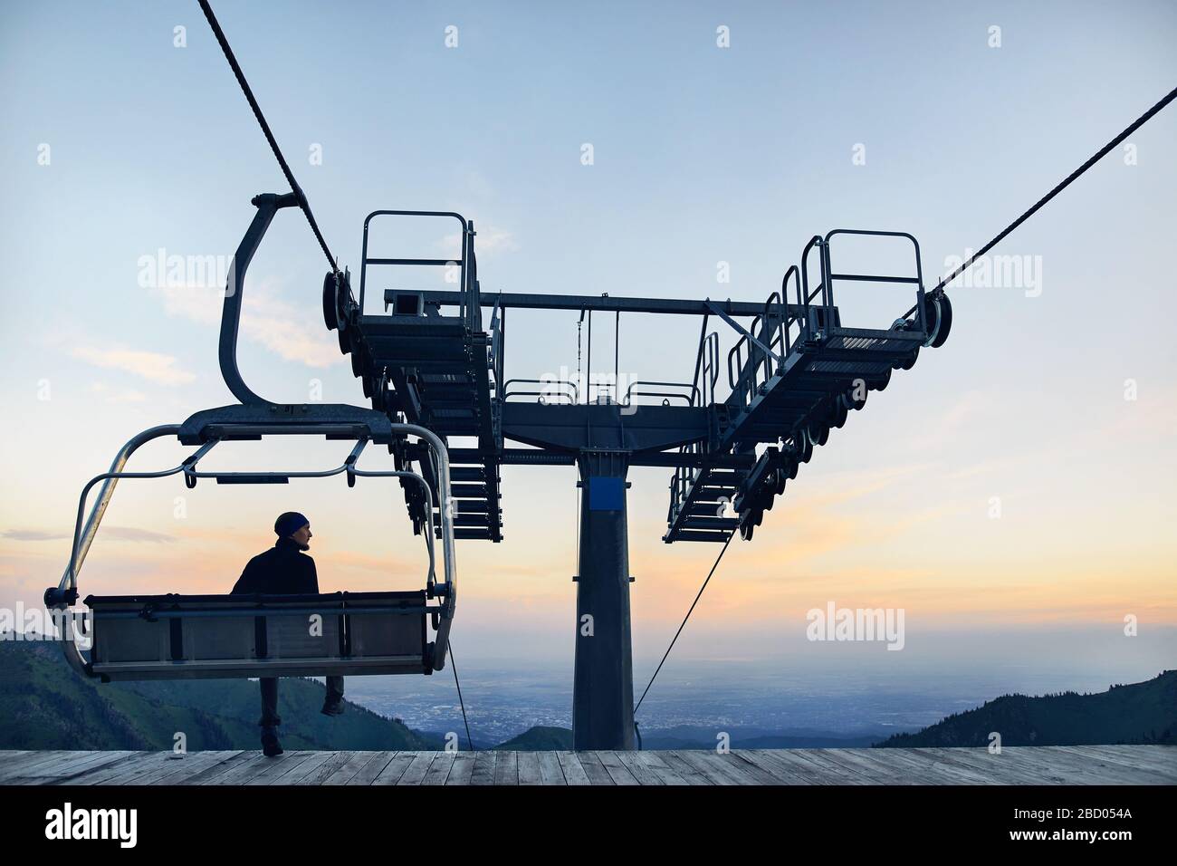 Tourist uomo seduto su una sedia in seggiovia in silhouette alta in mountain ski resort di sunrise Foto Stock